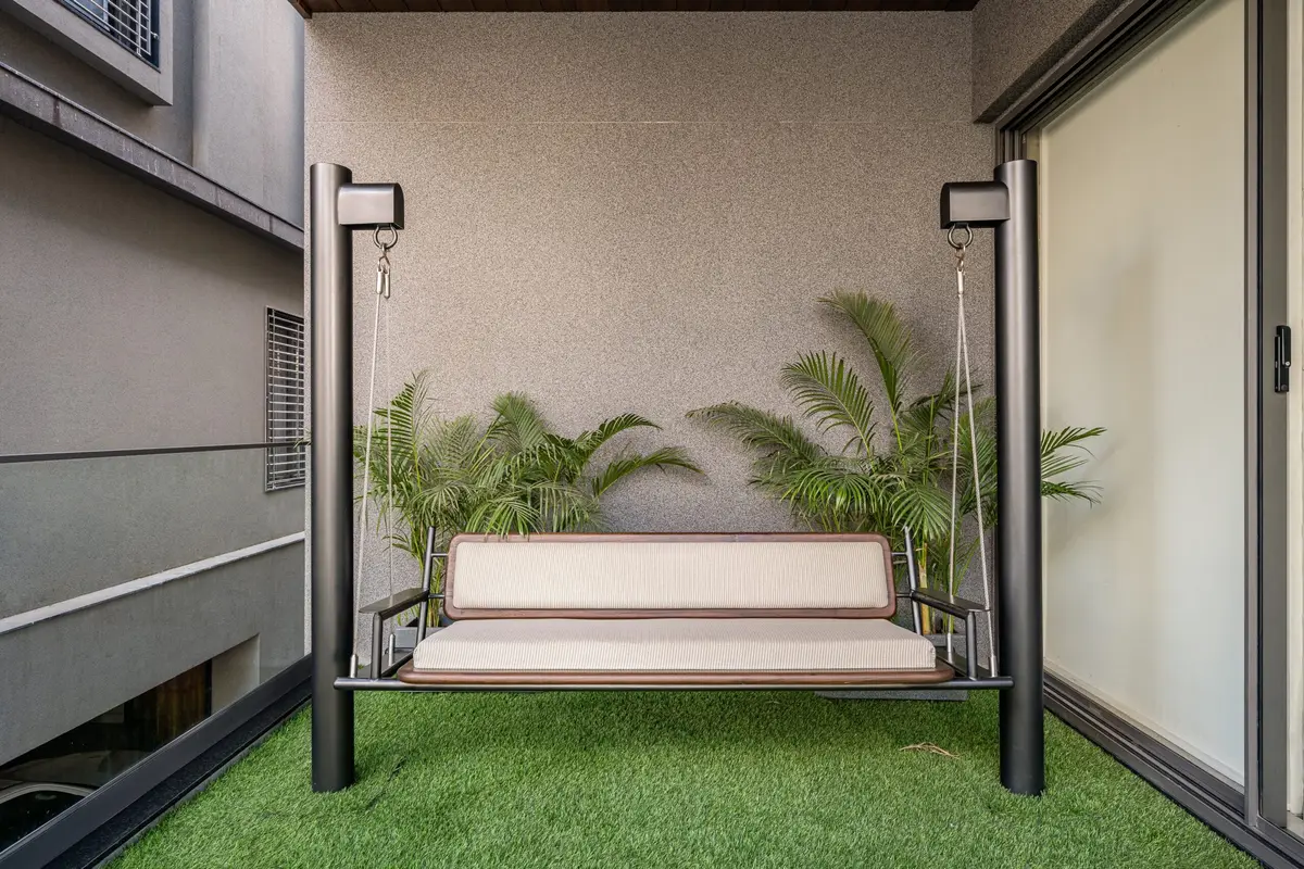 Balcony swing on artificial turf framed by tropical planting