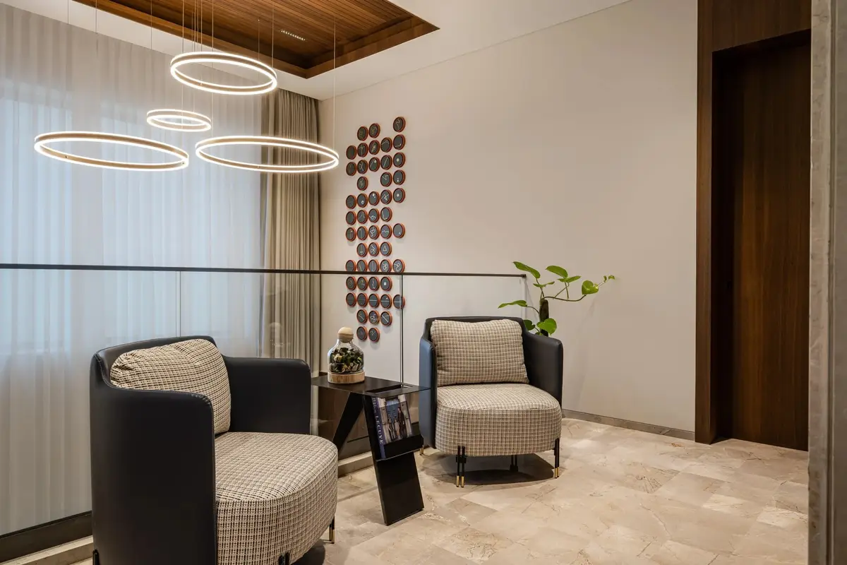 Sitting area with sculptural armchairs beneath a cluster of ring chandeliers